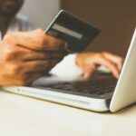 Pessoa usando cartão e notebook em uma compra online